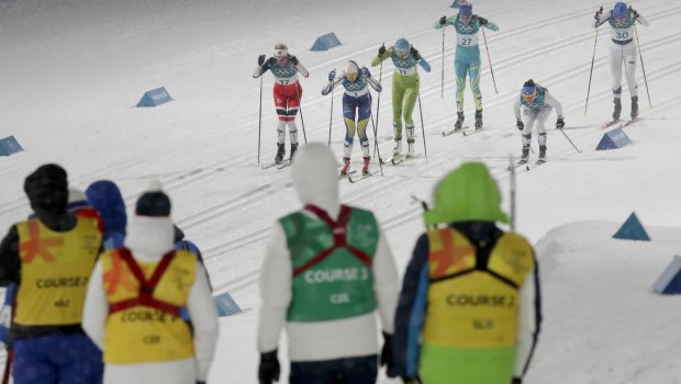 Workers watch the women's cross-country skiing.