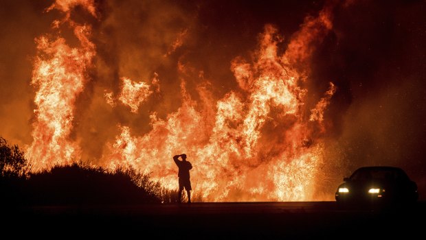 A motorist watches the flames from the Thomas fire in California from Highway 101 last month.