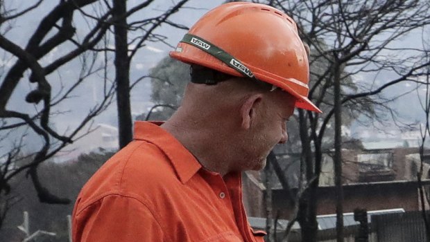 An electricity worker inspects properties on Wildlife Drive in Tathra after the bushfire.