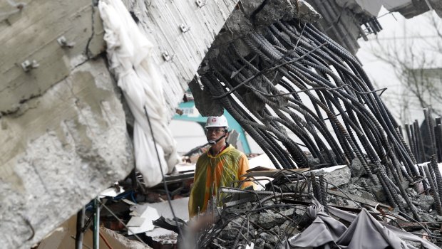 A rescuer checks damage during a search operation at a collapsed apartment building. 