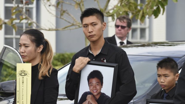 Jason Wang, centre, holds a picture of his brother Peter, along with his younger brother, Alex, after his brother's funeral in Coral Springs, Florida.