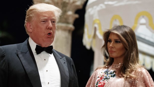 First lady Melania Trump looks on as President Donald Trump speaks with reporters after arriving for a New Year's Eve gala at his Mar-a-Lago resort.
