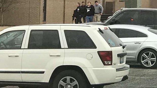 Police escort a person, second from right, out of the Marshall County High School after shooting there in Benton, Kentucky.