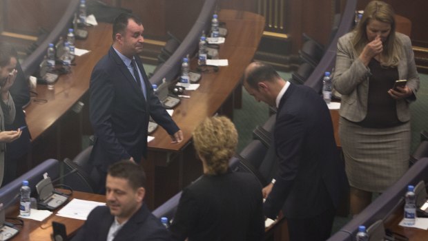 Kosovo lawmakers leave as smoke fills the auditorium of the Kosovo assembly.