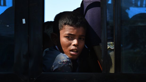 A Rohingya refugee boy peers out the window of a bus that will take the newly arrived refugees to camps in Bangladesh. 