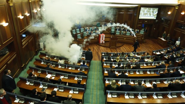 Opposition lawmakers throw a tear gas canister disrupting a parliamentary session in Kosovo on Wednesday.