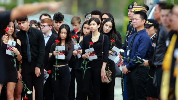 Mourners hold flowers during the funeral for Peter Wang, who was killed at Marjory Stoneman Douglas High School.