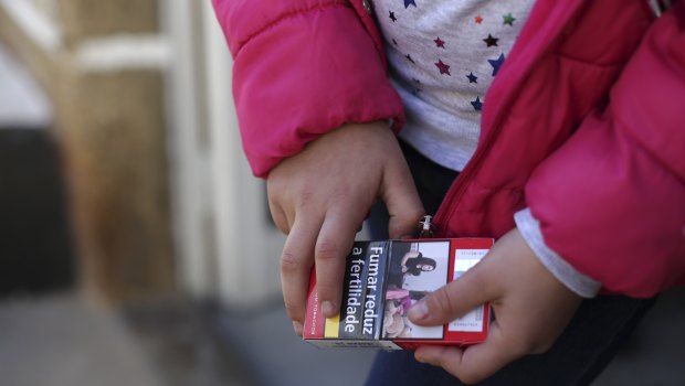 Natasha, 8 years old, holds a packet of cigarettes in the village of Vale de Salgueiro, northern Portugal.