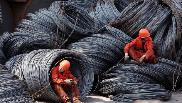 Workers take a break while sitting on a pile of steel wires at a stockyard run by the Shanghai Yirong Trading Co.