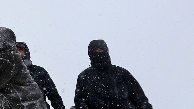 Military veterans huddle together to hold a United States flag against strong winds during a march to a closed bridge outside the Oceti Sakowin camp to protest the Dakota Access oil pipeline in Cannon Ball, ND.