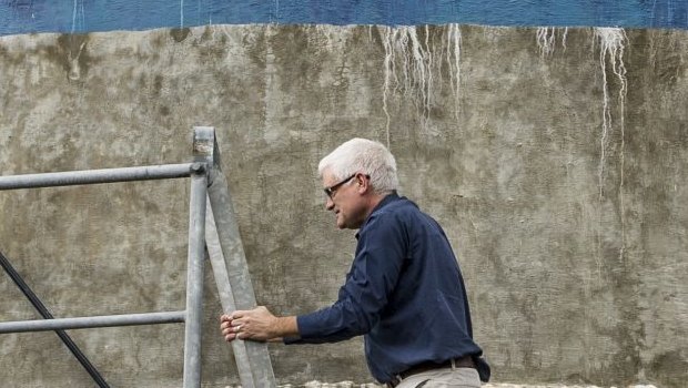 Matthew Nott, president of the Clean Energy For Eternity group, stands next to a sign that he painted on the Tathra Water tower, in 2016.