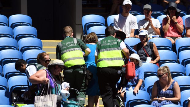 A spectator is treated by ambulance officials in soaring heat at the Australian Open on Thursday, January 18.
