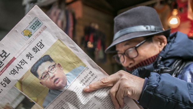 A  man reads a copy of Seoul's Munhwa Ilbo newspaper featuring Donald Trump and Kim Jong-un on the front page.