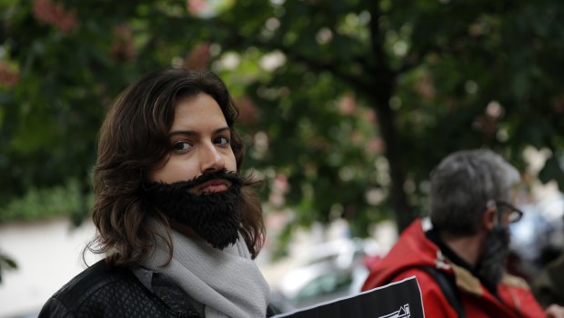 A woman with a fake beard attends a protest to demand an end to widespread sexism in French politics.