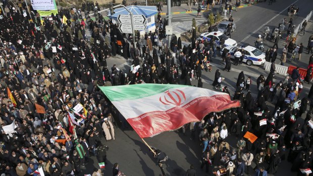 A demonstrator waves a huge Iranian flag during a pro-government rally in the northeastern city of Mashhad, Iran.