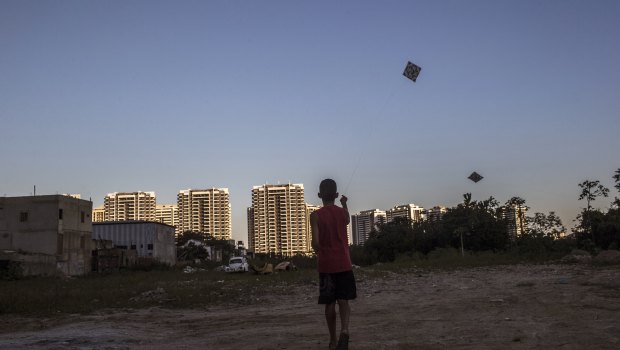 A boy flies a kite in an empty lot in front of the Ilha Pura property, 3604 empty luxury apartments used by more than 18,000 athletes during the Olympic games.