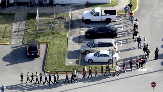 Students are evacuated by police from Marjory Stoneman Douglas High School following the shooting.