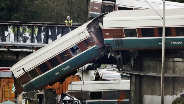 An investigator takes photos off a railroad bridge at the scene of where an Amtrak train derailed in DuPont, Washington. 