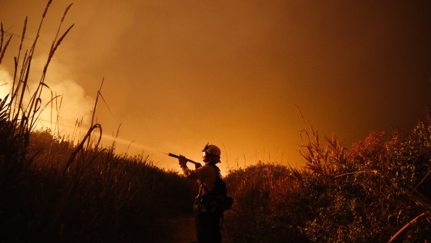Firefighter Ryan Spencer battles a wildfire as it burns along a hillside toward homes in La Conchita, California in December.