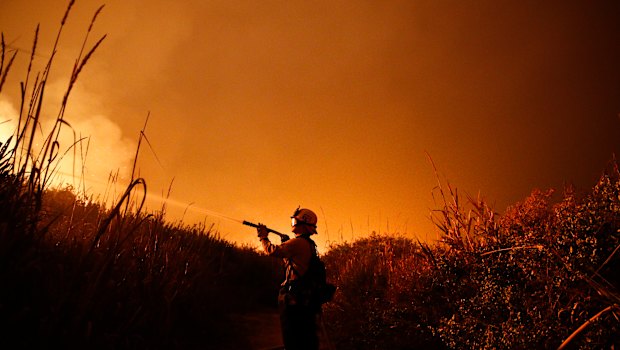 Firefighter Ryan Spencer battles a wildfire as it burns along a hillside toward homes in La Conchita, California in December.