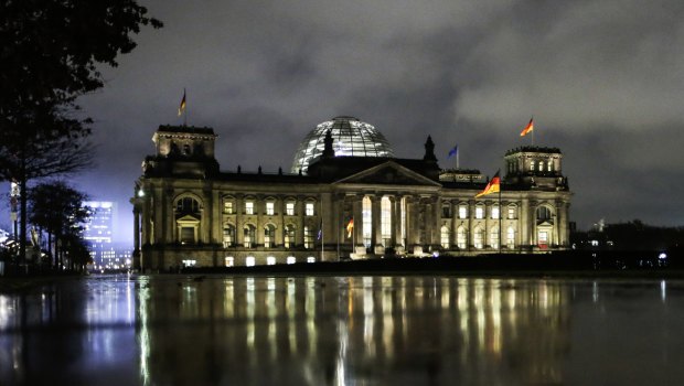 The Reichstag, the building of German parliament Bundestag, is reflected in a puddle in Berlin.