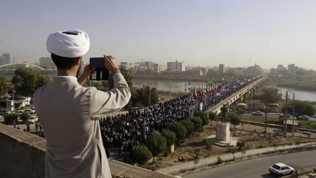 In this photo provided by the Iranian Students' News Agency, a clergyman takes a picture of a pro-government demonstration in the southwestern city of Ahvaz, Iran.</p>
<p>