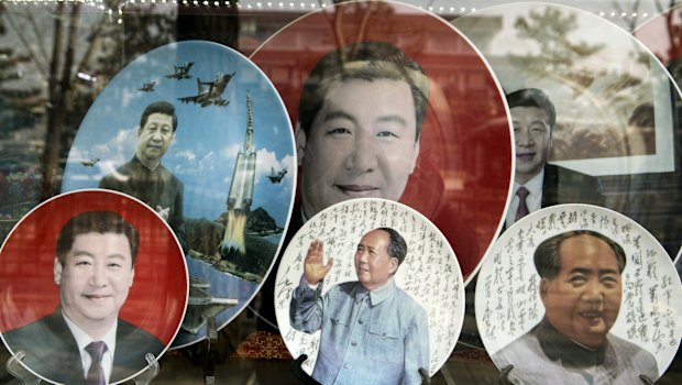 Porcelain plates featuring portraits of former Chinese leader Mao Zedong, bottom second right and bottom right, and Chinese President Xi Jinping are displayed in a shop window in Beijing.