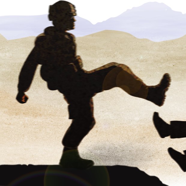 A special forces soldier kicks an Afghan prisoner.