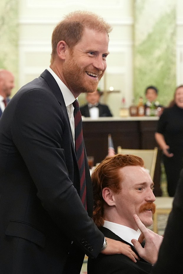 Prince Harry, the Duke of Sussex, talks about red hair with William Bringer as he arrives to speak at a roundtable about support for veterans
