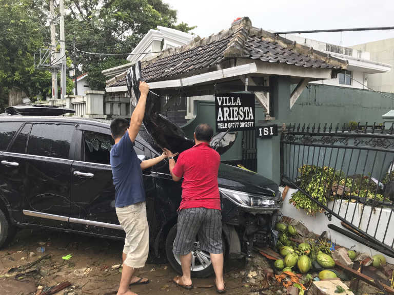 Kevin Resali, 36, removes the windscreen of his car with a friend so he can retrieve belongings from it.