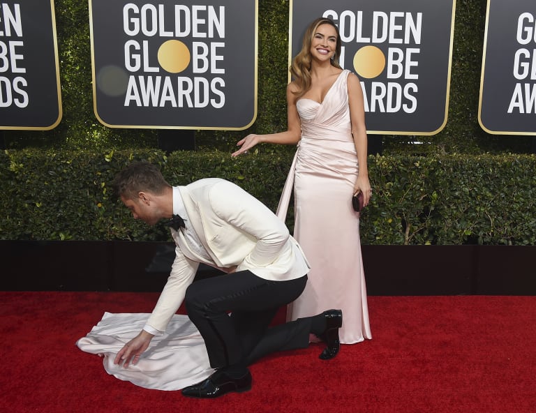 Justin Hartley adjusts Chrishell Stause dress as they arrive at the 76th annual Golden Globe Awards at the Beverly Hilton Hotel on Sunday, Jan. 6, 2019, in Beverly Hills, Calif. (Photo by Jordan Strauss/Invision/AP)