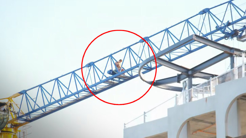 Man scales crane at construction site in Melbourne