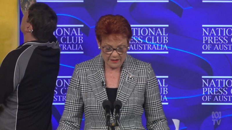 Banner Unfurls Behind Pauline Hanson During Press Club Speech
