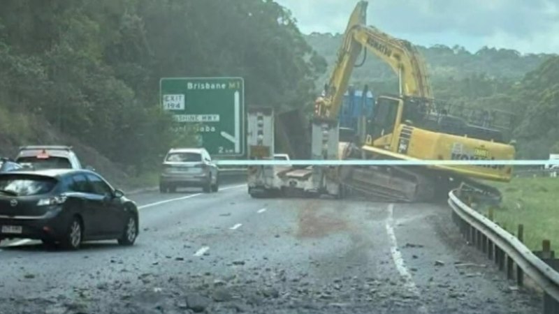 Truck carrying excavator hits overhead bridge