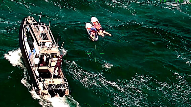 Paddleboarders being rescued after being swept across the bay