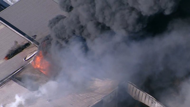 Smoke billows across Sydney’s south-west as huge industrial fire burns