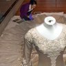 Specialist Textile Installer, Keira Millar from the Victorian and Albert Museum inspects a dress at the Bendigo Art Gallery Wedding Dress Exhibition 