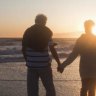 Senior couple holding hands on beach at sunset
 Getty Images