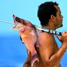 Belize, fisherman with catch slung over shoulder. 