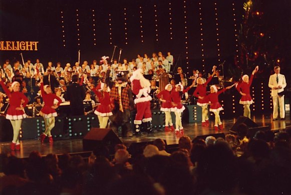 Santa and his helpers dance up a treat at the 1982 Carols by Candlelight concert, with Brian Naylor and Humphrey B. Bear joining them on stage, alongside the Salvation Army band.

