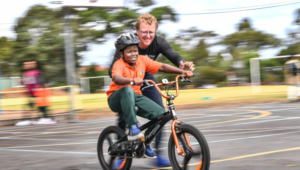 Smile says it all: Abdul Popoola masters a donated bike, his first, with help from Bart Sbeghen, co-founder of Dr Cranky's Bikes for Kids, at Clayton North Primary School. 