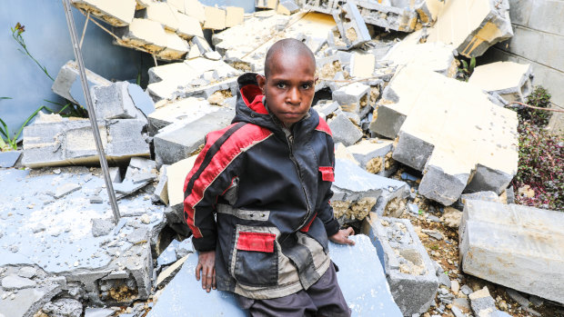 Abel Jeffery, 10, in front of the damaged Mendi School of Nursing, where 5 buildings were seriously damaged. 