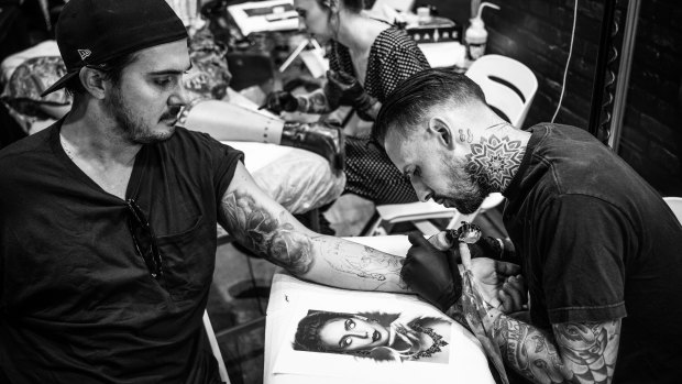 Elric Gordon focuses on a tattoo on a client at the Australian Tattoo Expo. 
