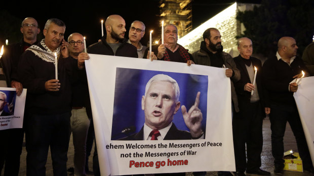 Palestinians hold posters showing US Vice President Mike Pence during a protests against his visit near the Church of the Nativity in Bethlehem, on Sunday,