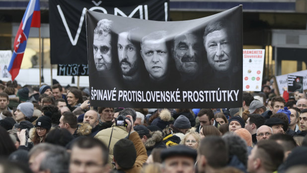 Demonstrators hold a poster reading 'Dirty anti-Slovak prostitutes' with Prime Minister Robert Fico in the middle, his Interior Minister Robert Kalinak (to Fico's right), and national police chief Tibor Gaspar, right, during an anti-government rally in Bratislava, Slovakia, on  March 9.