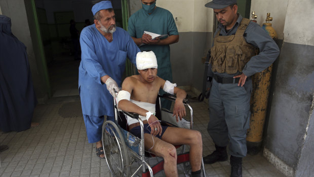 An injured man is moved by wheelchair at a hospital following the suicide attack in front of Kabul University.