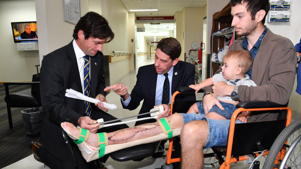 Surgeon Dr Michael Wagels and Queensland Health Minister Cameron Dick discuss the operation with Reuben Lichter and his son, William.