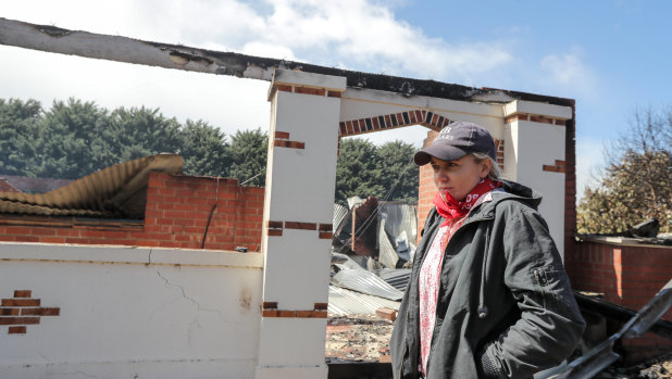 Gazette Homestead resident Elle Moyle in front of her brother's burnt-out house.
