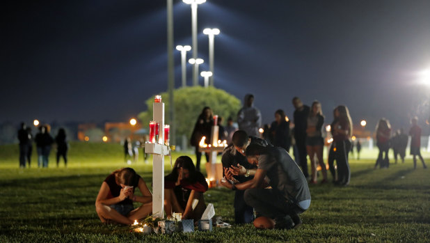 People pray around one of seventeen crosses, after a candlelight vigil for the victims.