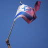 A demonstrator waves a coloured Israeli flag during a protest.